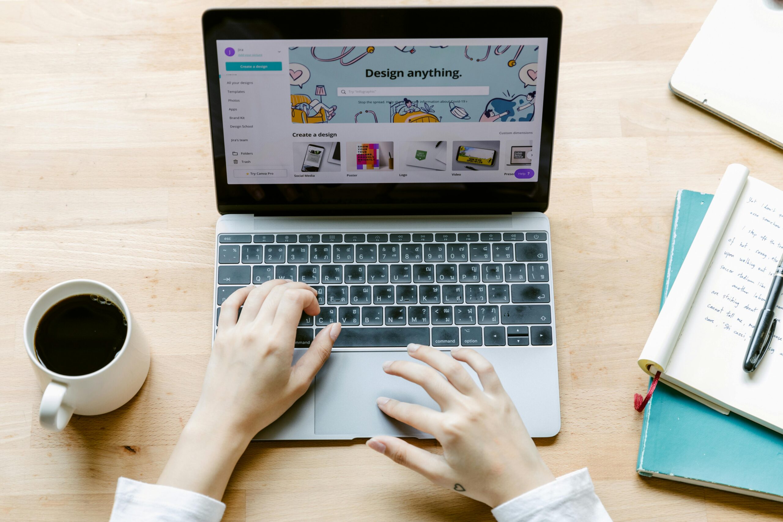 Overhead shot of hands typing on a laptop with coffee and notes, perfect for freelance and work-from-home themes.